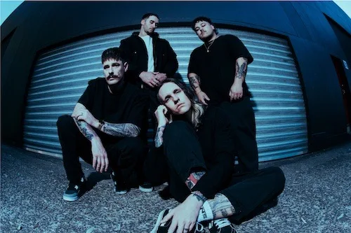 Ocean Sleeper band photo four band members sitting in front of a garage type door staring at camera view, dark background