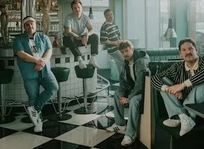 Rising Insane band photo Five band members sitting in type of diner staring in camera view.