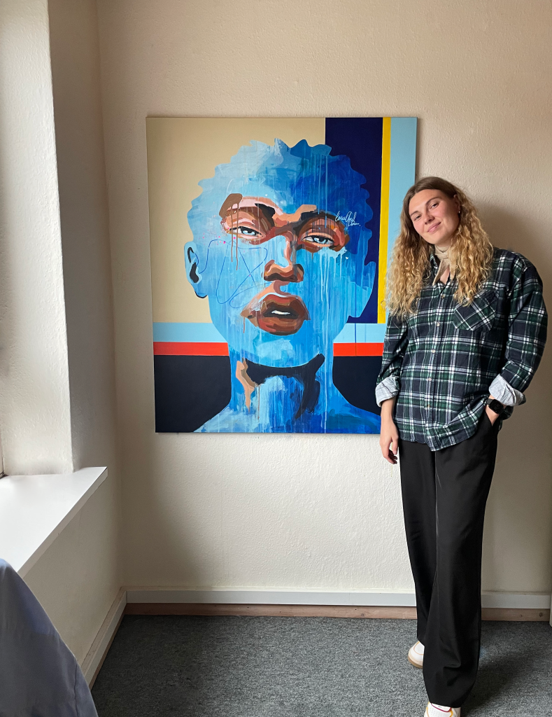 Maleriet "Ezra" hængende på væg med Mette stående foran