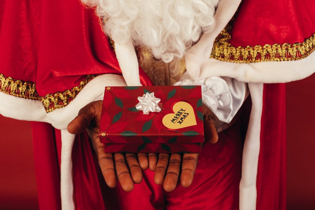 person wearing santa claus outfit while holding christmas gift