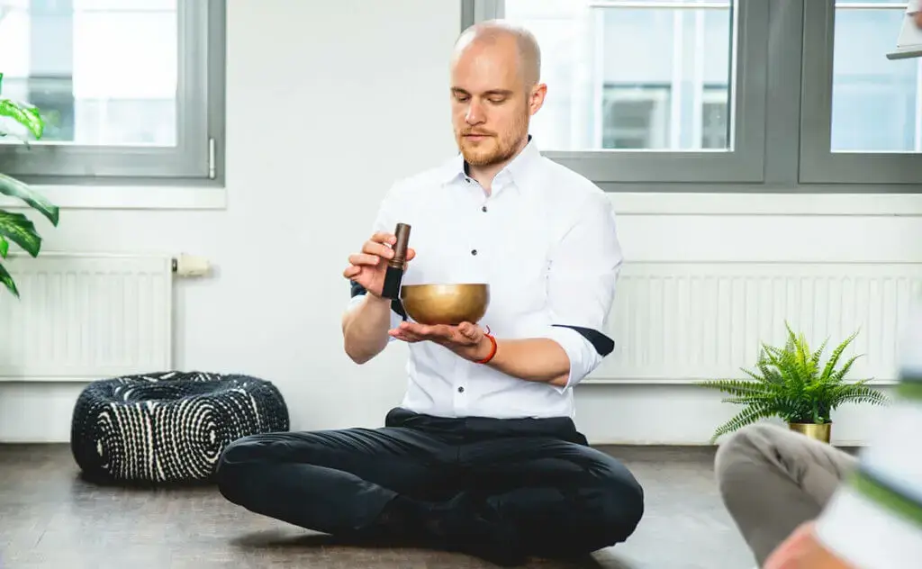 Philipp Pham ist bereit für eine Meditation mit der Klangschale in einem modernen Raum.