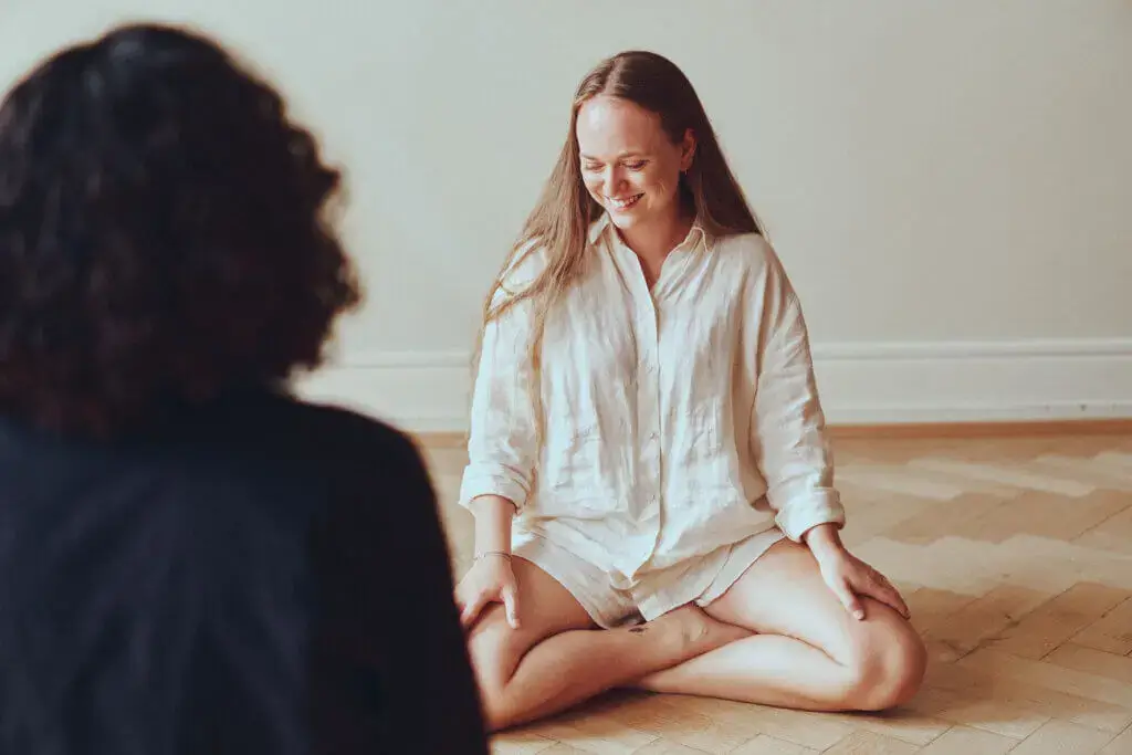 Ein Mädchen, das zusammen mit einer Frau in einem ruhigen Raum Metta Meditation macht.
