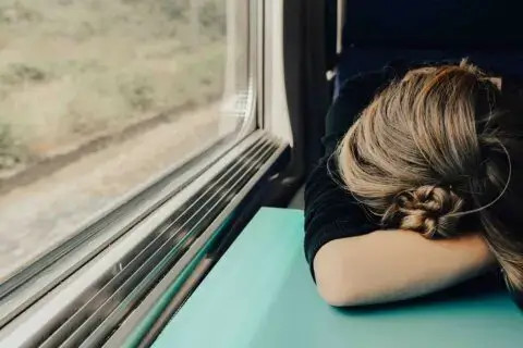 Ein Mädchen in einem Zug, das unter Zeit- und Leistungsdruck leidet und eingeschlafen ist.