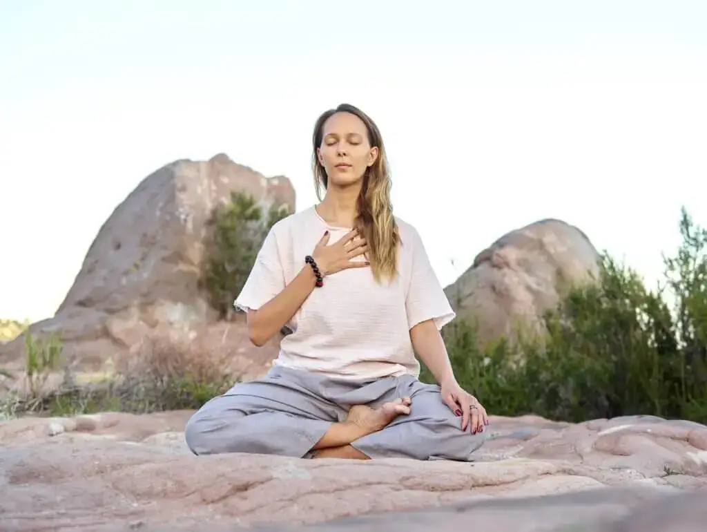Ein Mädchen macht auf Steinen im Gebirge Dankbarkeit-Meditation.