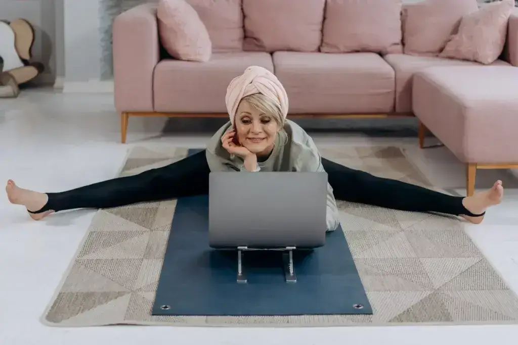 Eine alte Frau, die auf einem Rechner liegend auf dem Boden arbeitet.