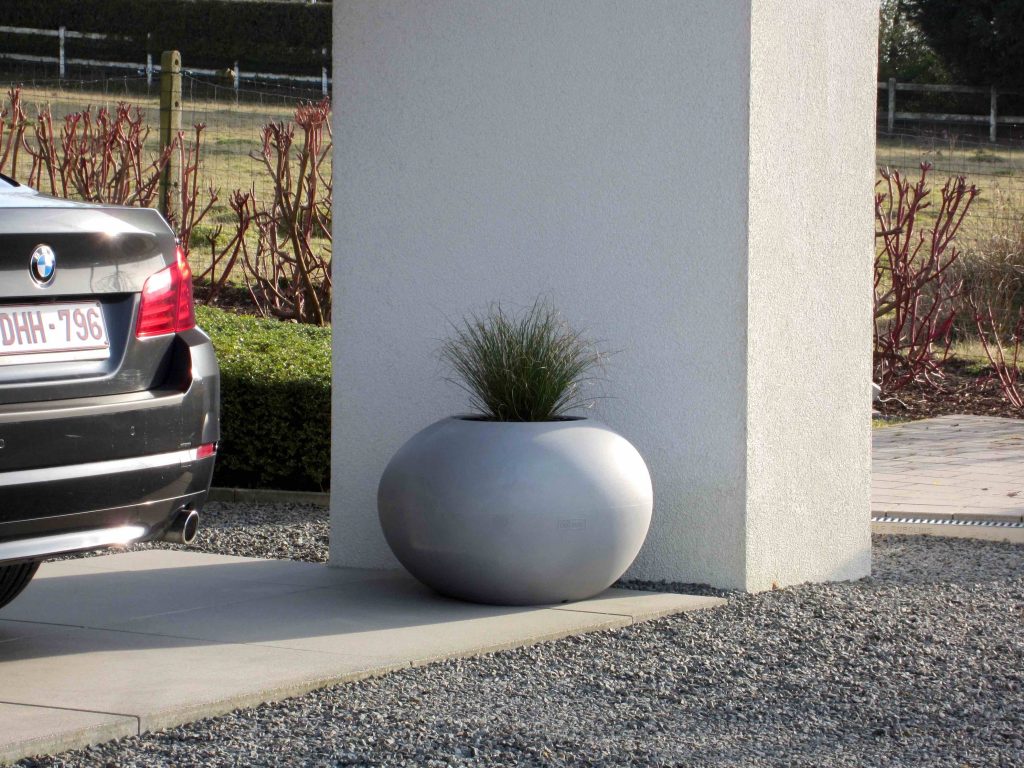Keivormige bloempot in de voortuin onder de carport Keivormige bloempot in de voortuin onder de carport