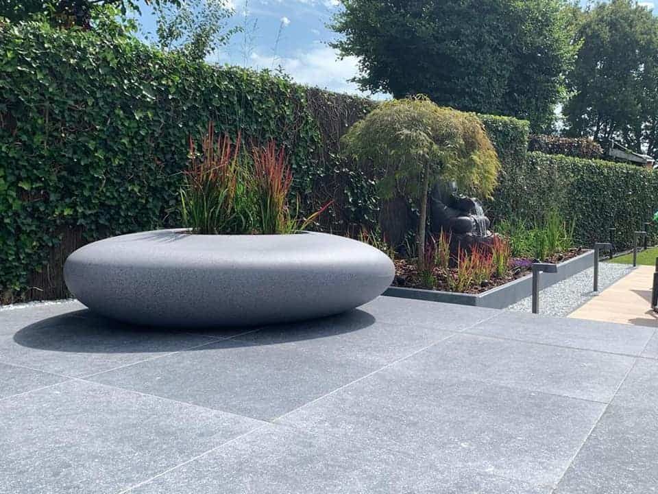 MiStorus rivierkei en bloembak op terras van keramische tegels met de look van natuursteen. MiStorus rivierkei en bloembak op terras van keramische tegels met de look van natuursteen.