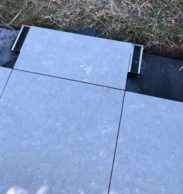 Terras van keramische tegels gelegd op tegeldragers met rand-fix stabilisatie-elementen aan de uiteinden. Terras van keramische tegels gelegd op tegeldragers met rand-fix stabilisatie-elementen aan de uiteinden.