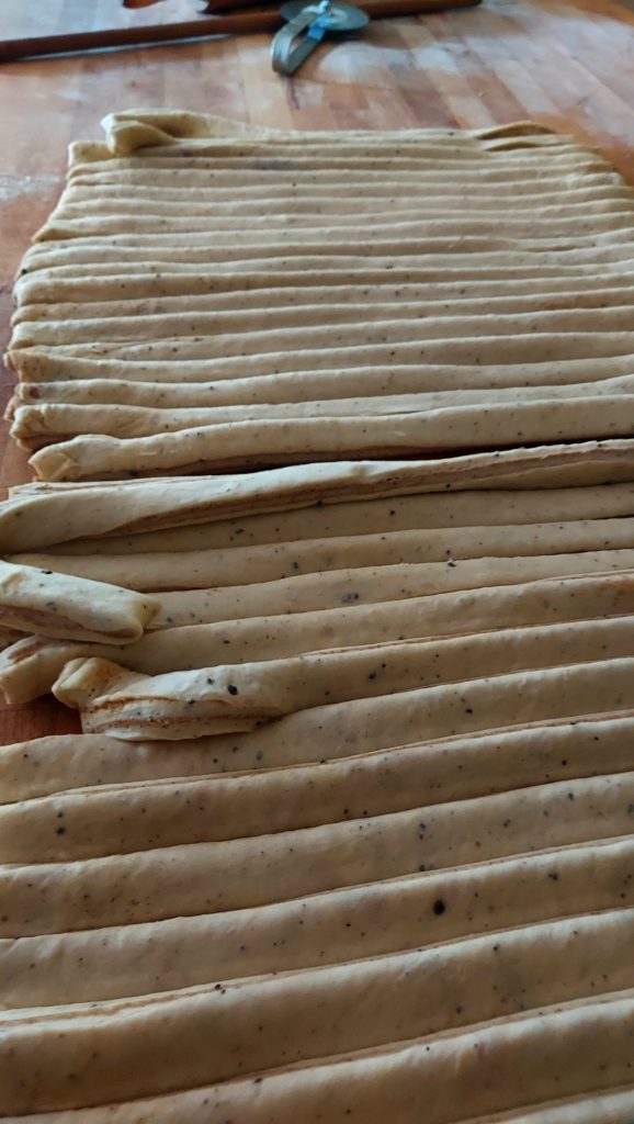 Cut the dough into strips and twist them into buns. Place the buns on a baking tray lined with parchment paper.