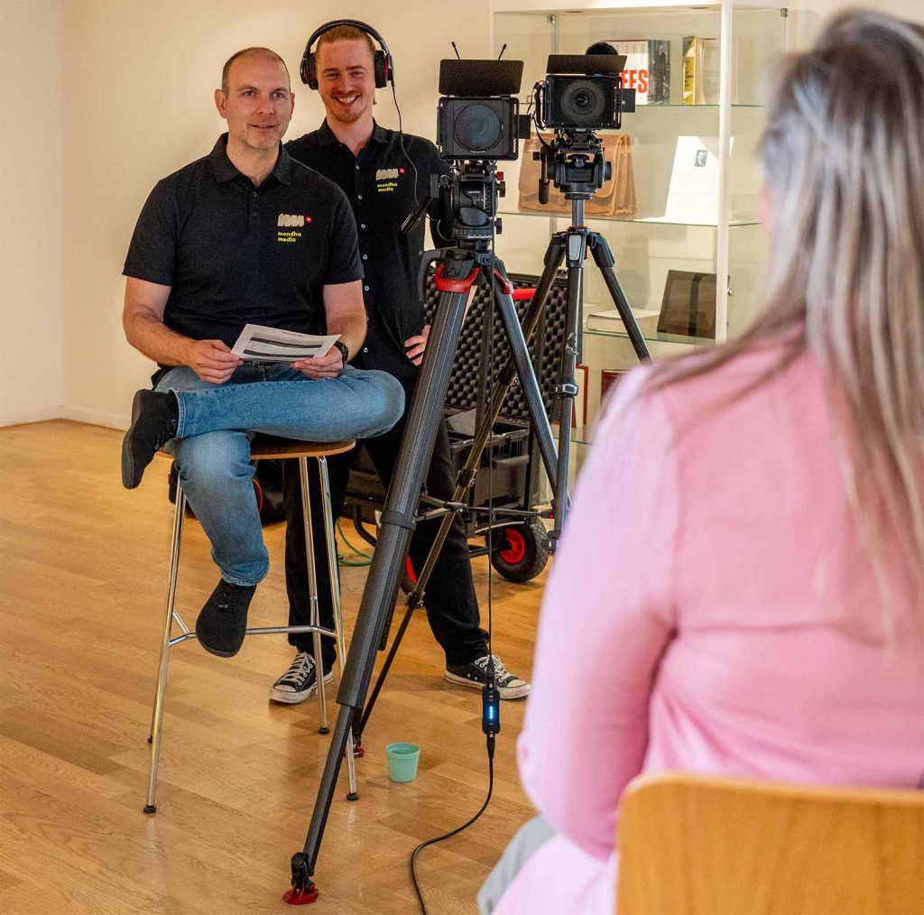 Een interview setting waar Tim en Sebastiaan van Mondha Media tegenover degene zitten die geinterviewd wordt. We zien ook twee filmcamera's