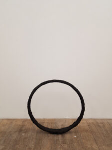 En bild från en utställning på ett galleri som visar en skulptur i cirkelform av gips. A picture of a sculpture during an exhibition at a gallery.