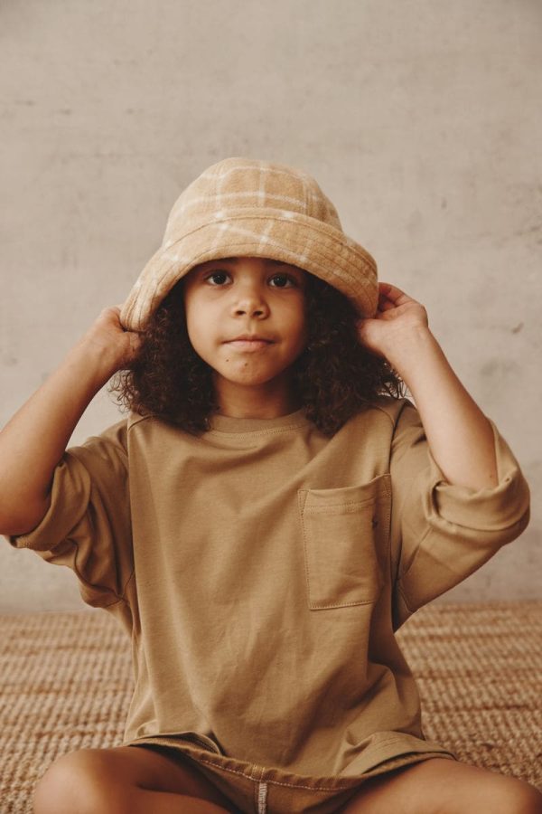 girl wearing the Joan Check Bucket Hat in beige paired with the Duncan Longsleeve in Khaki by the brand Alfred