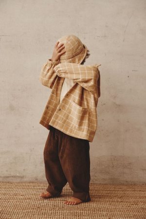 boy wearing the Joan Check Jacket & Hat in beige paired with the Barney Pants by the brand Alfred