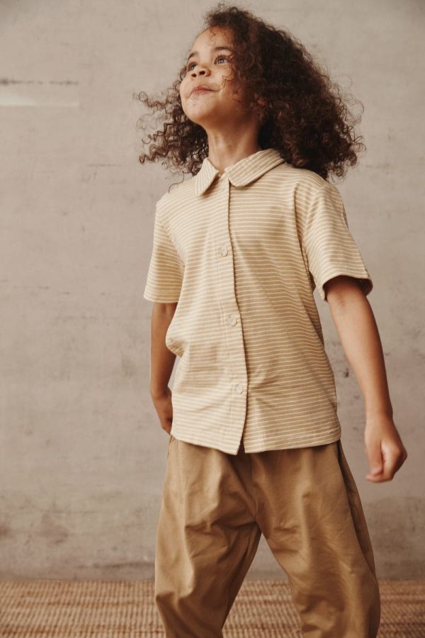 girl wearing the Theodore Shirt in Cream paired with the Duncan Pants in Khaki by the brand Alfred