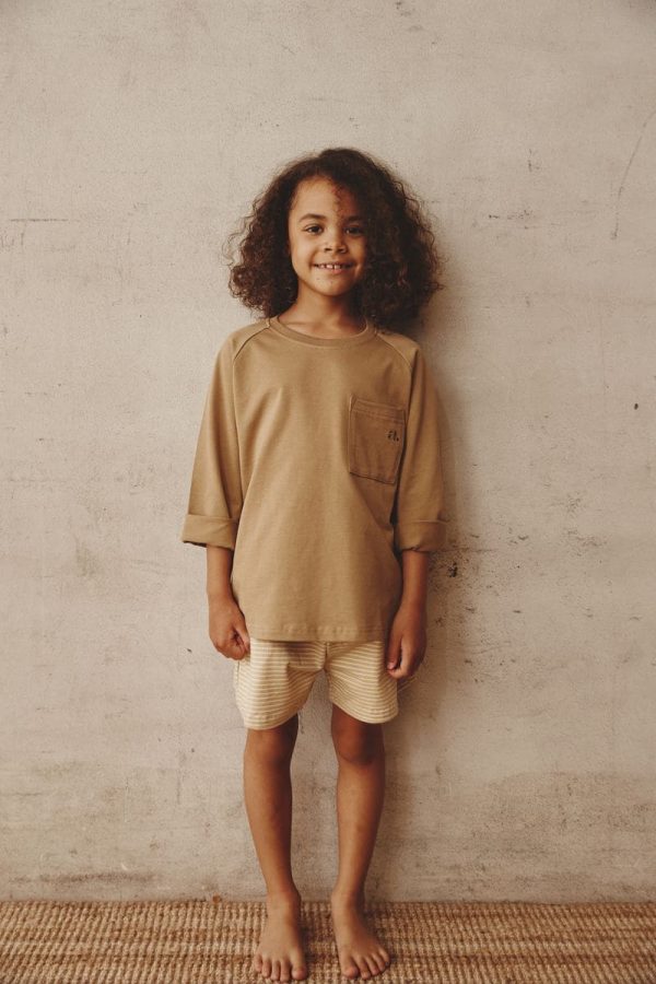 girl wearing the Theodore Shorts in Cream paired with the Duncan Longsleeve in Khaki by the brand Alfred