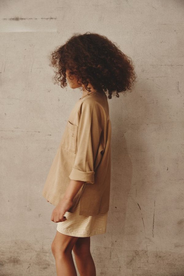 girl wearing the Theodore Shorts in Cream paired with the Duncan Longsleeve in Khaki by the brand Alfred