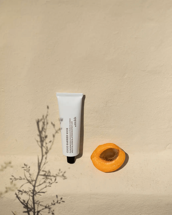 the Good Barrier Mask of By Mukk styled next to an apricot which is one of the products main active ingredients