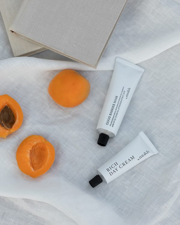 the Good Barrier Mask of By Mukk styled next to a few apricots which is one of the product's main active ingredients