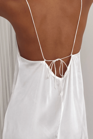 Detailed back view of a woman wearing the Jai Dress in White by the brand Bahhgoose, showing the adjustable tie straps and the open back of the dress