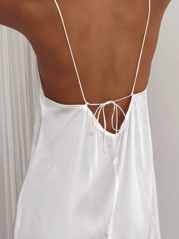 Detailed back view of a woman wearing the Jai Dress in White by the brand Bahhgoose, showing the adjustable tie straps and the open back of the dress