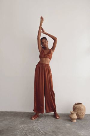 a woman wearing the Jai Pants in Coco by the brand Bahhgoose, showing the relaxed fit and the silky fabric