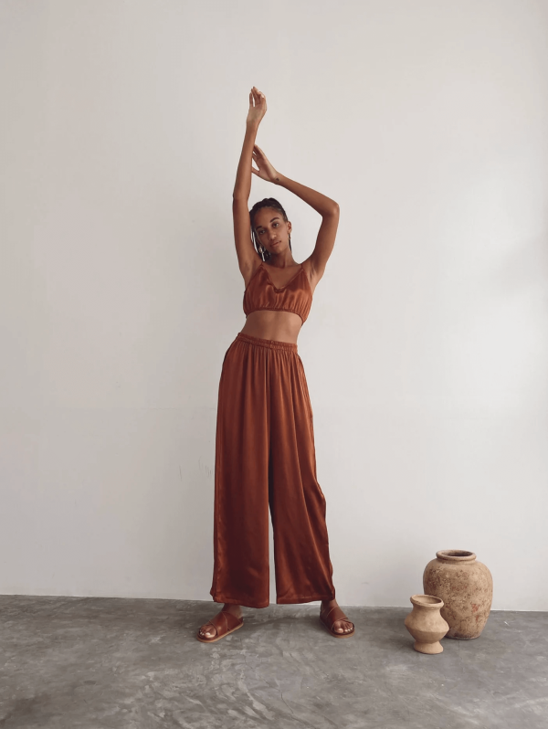 a woman wearing the Jai Pants in Coco by the brand Bahhgoose, showing the relaxed fit and the silky fabric