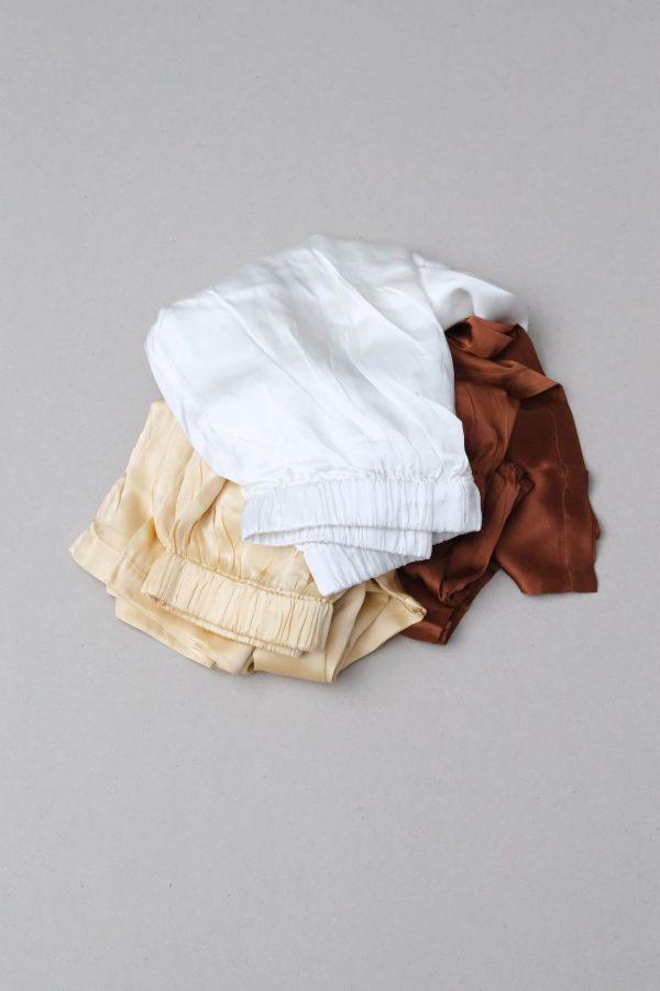 flatlay of all three colours of the silk Jai Pants in Yellow, White and Coco, by the brand Bahhgoose
