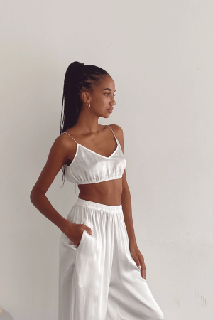 Closeup of a woman wearing the Jai Pants in White by the brand Bahhgoose, showing the relaxed fit of this beautiful co-ord set