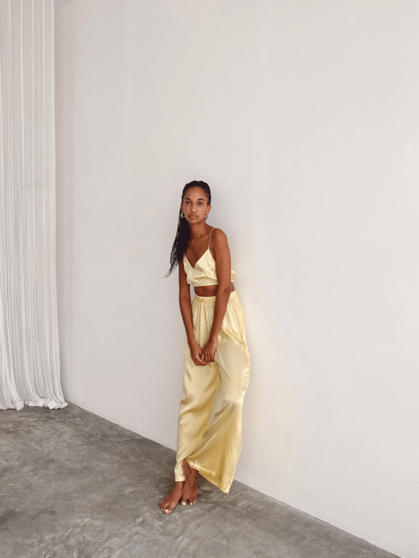 a woman wearing the Jai Pants in Yellow by the brand Bahhgoose, showing the relaxed fit and the silky fabric
