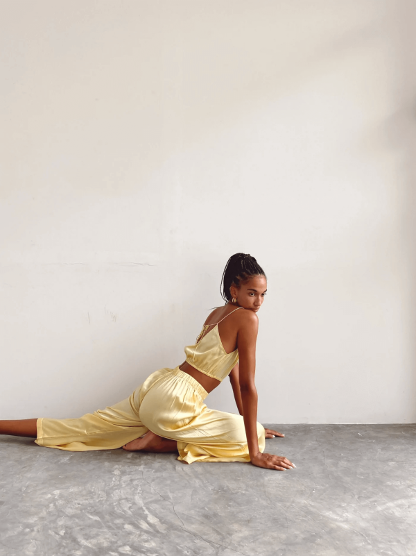 woman sitting down while wearing the Jai Pants in Yellow by the brand Bahhgoose, showing the relaxed fit of the pant