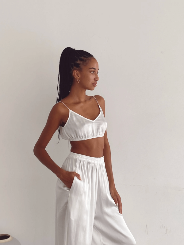 Closeup of a woman wearing the Jai Top with the matching Jai Pants in White by the brand Bahhgoose, showing the relaxed fit of this beautiful co-ord set