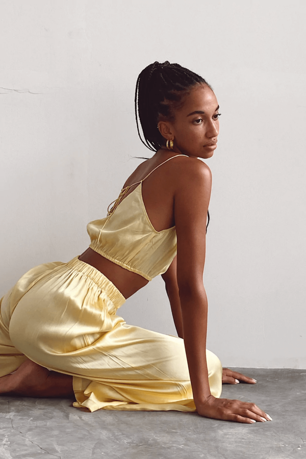 a woman sitting while wearing the Jai Top in Yellow by the brand Bahhgoose, showing the relaxed fit of this beautiful co-ord set