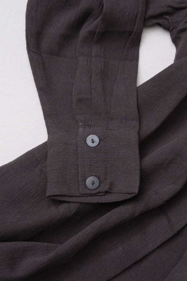 detailed flatlay of the Ker Button Up in Charcoal by the brand Bahhgoose, showing the cuff sleeve and the textured fabric