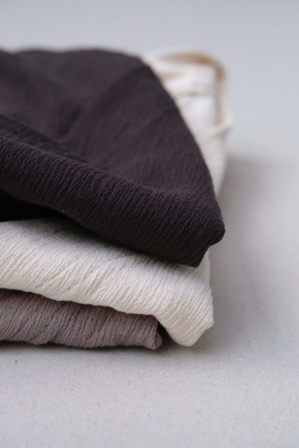 folded pile of Ona Button Ups in Charcoal, Natural and Taupe, by the brand Bahhgoose