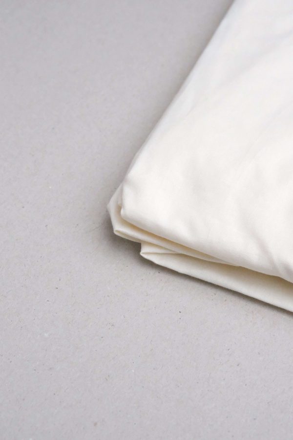 flatlay of the Base Cotton Fitted Bedsheet in Vanilla by the brand Cats and Boys