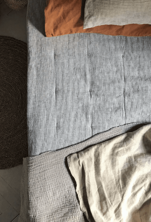 the linen topstitched quilt in grey stripes by the brand Cats and Boys