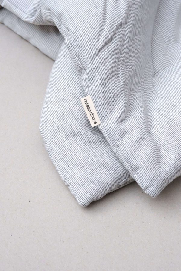 flatlay of the linen topstitched quilt in grey stripes by the brand Cats and Boys