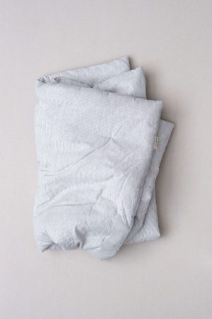 flatlay of the linen topstitched quilt in grey stripes by the brand Cats and Boys