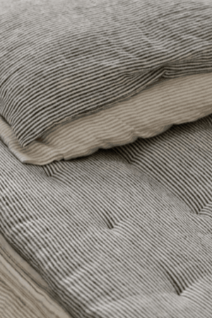 the linen topstitched quilt in grey stripes by the brand Cats and Boys