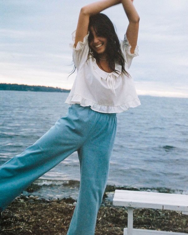 woman wearing the cotton Aura Pants in Light Denim paired with the Doll Blouse by the brand Harly Jae