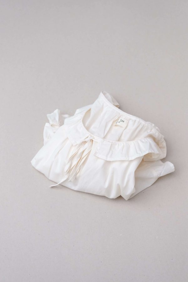 flatlay of the organic cotton Doll Blouse in Whipped Butter by the brand Harly Jae