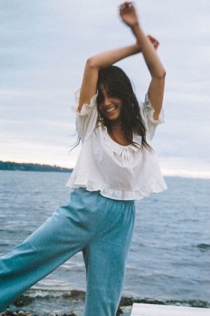 woman wearing the organic cotton Doll Blouse in Whipped Butter paired with the Aura Pants by the brand Harly Jae