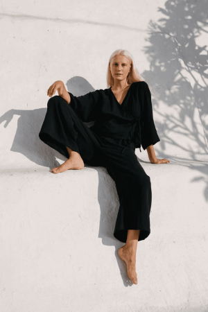 woman wearing the Mia Wrap Top & Poppy Pants in Black by the brand The Bare Road