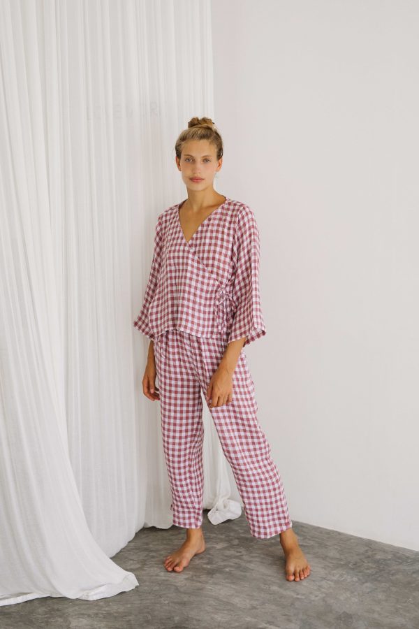 woman wearing the Mia Wrap Top & Mia Pants in Cherry Gingham by the brand The Bare Road