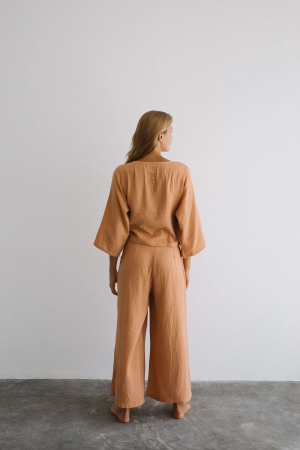 woman wearing the Mia Wrap Top & Poppy Pants in Peach by the brand The Bare Road