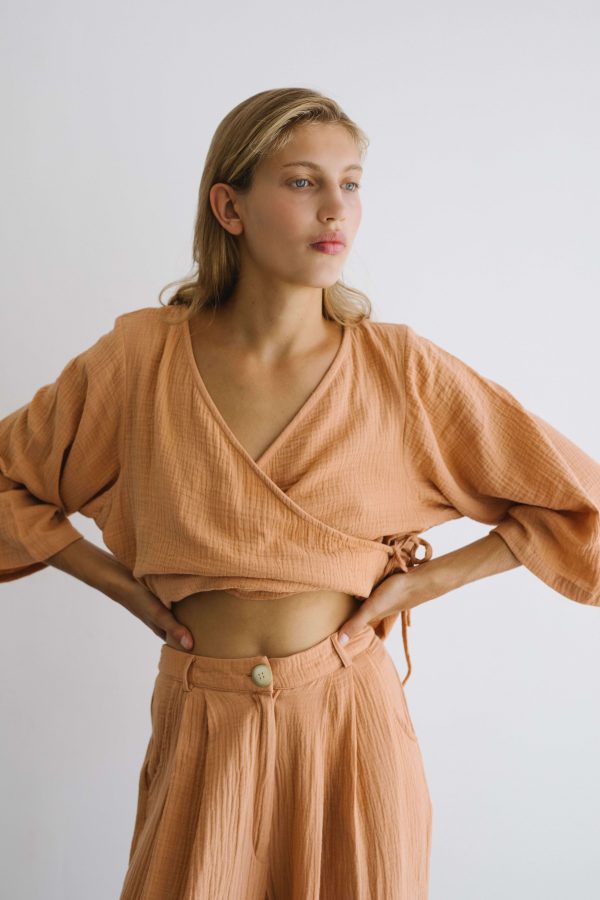 woman wearing the Mia Wrap Top in Peach by the brand The Bare Road