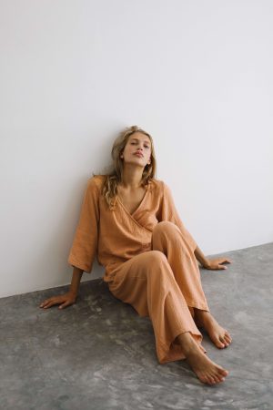 woman wearing the Mia Wrap Top & Poppy Pants in Peach by the brand The Bare Road