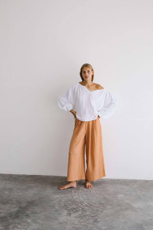 woman wearing the Poppy Pants in Peach by the brand The Bare Road