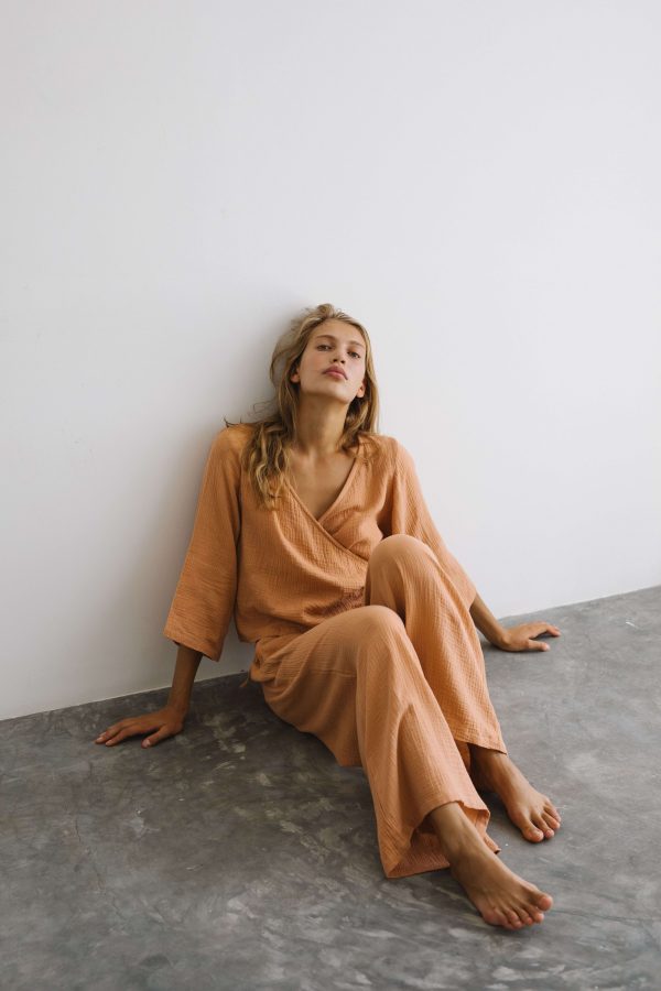 woman wearing the Poppy Pants & Mia Wrap Top in Peach by the brand The Bare Road
