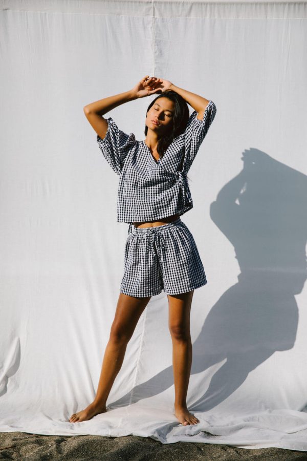 woman wearing the Ella Wrap Top & Maddie Shorts in Black Gingham by the brand The Bare Road